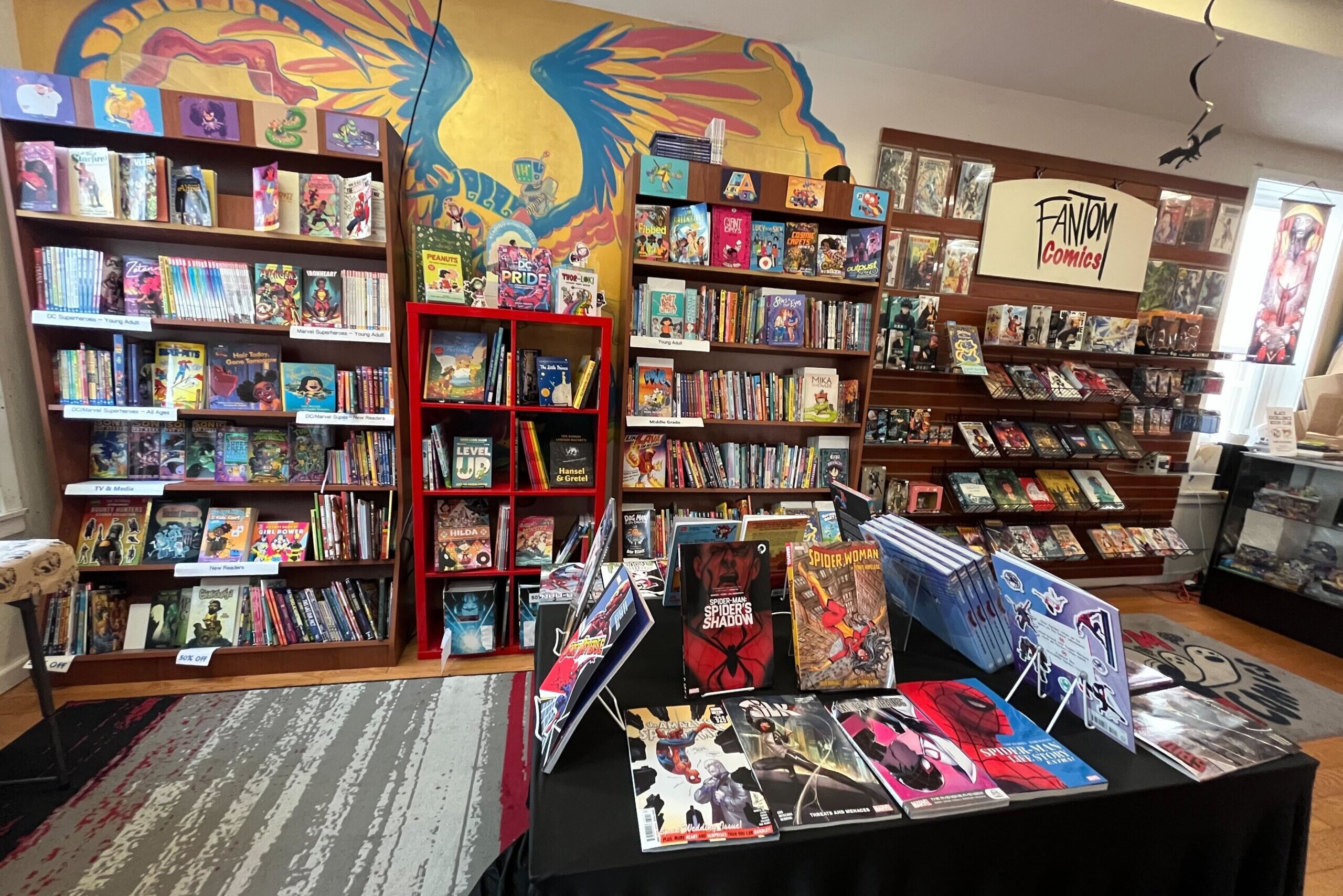 An interior shot of a comic book store, filled with shelves of comics and graphic novels.