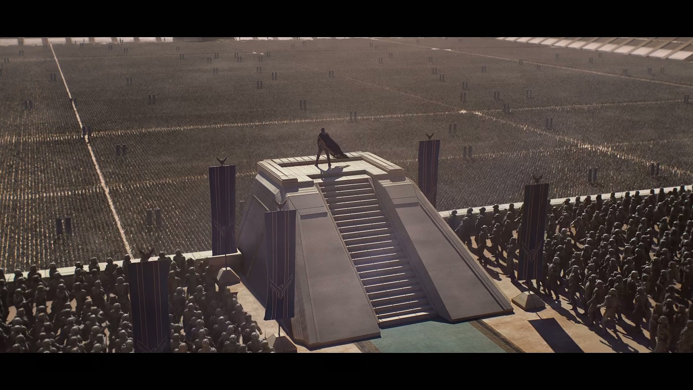 A lone figure on a stepped dais before a massed army