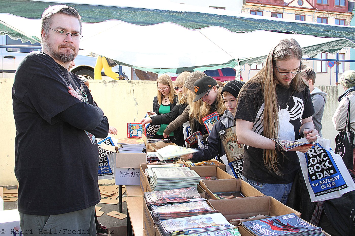 Comic book fans flipping through longboxes of comics at a Free Comic Book Day event