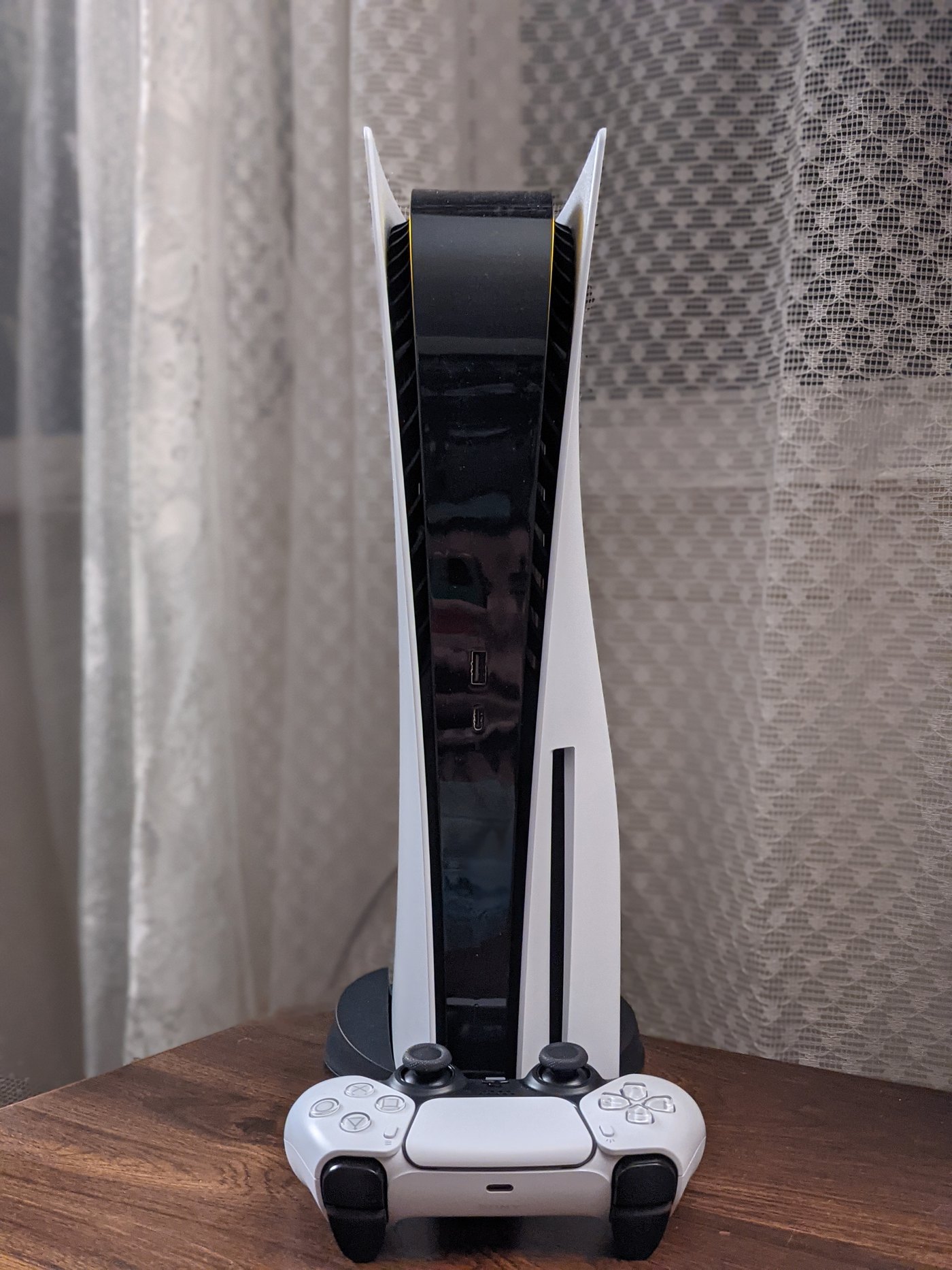A PlayStation 5 console standing upright beside a white DualSense controller