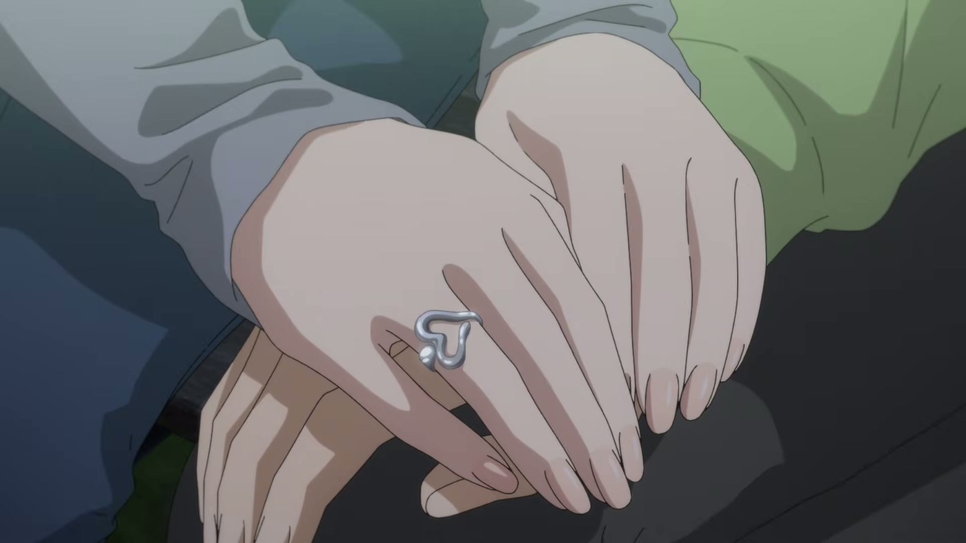Close-up of one hand holding another, a ring visible on the finger