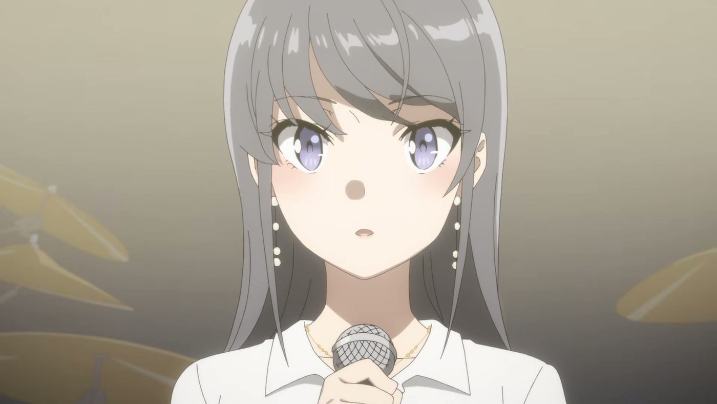 A silver-haired character in a white shirt holding a microphone under stage lights