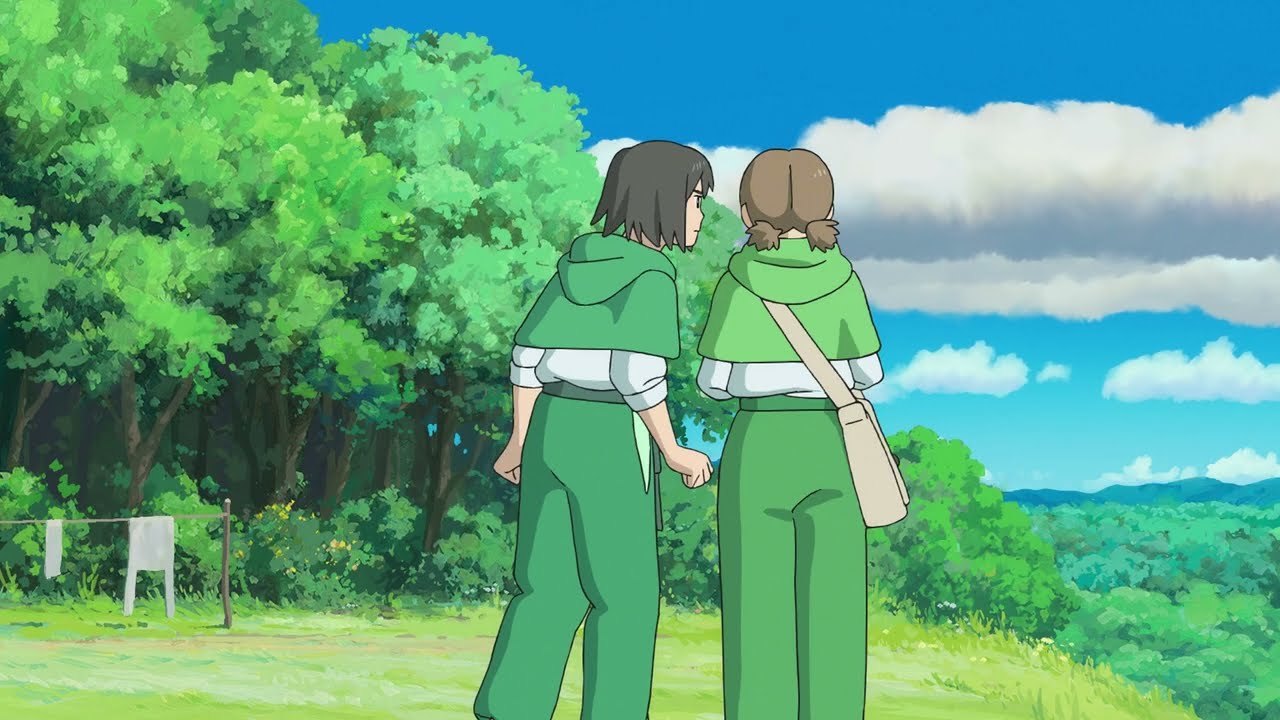 The two girls walking a green hillside in wartime-issue capes