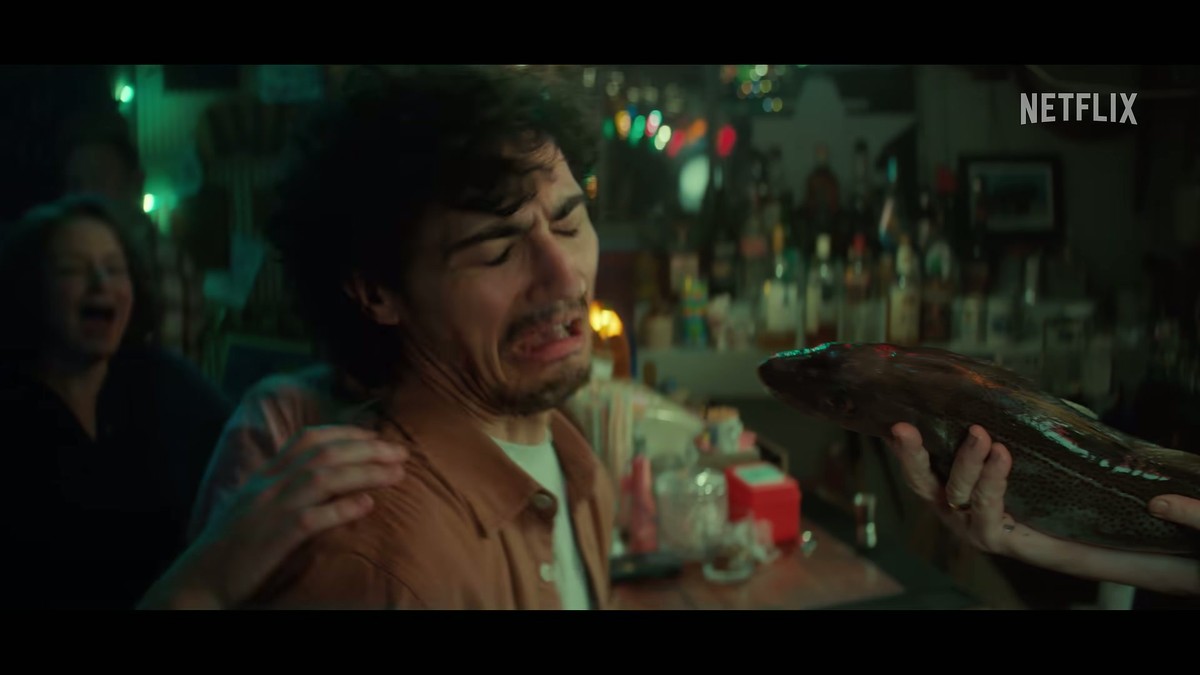 A man recoiling after kissing a cod during a screech-in in the Below trailer