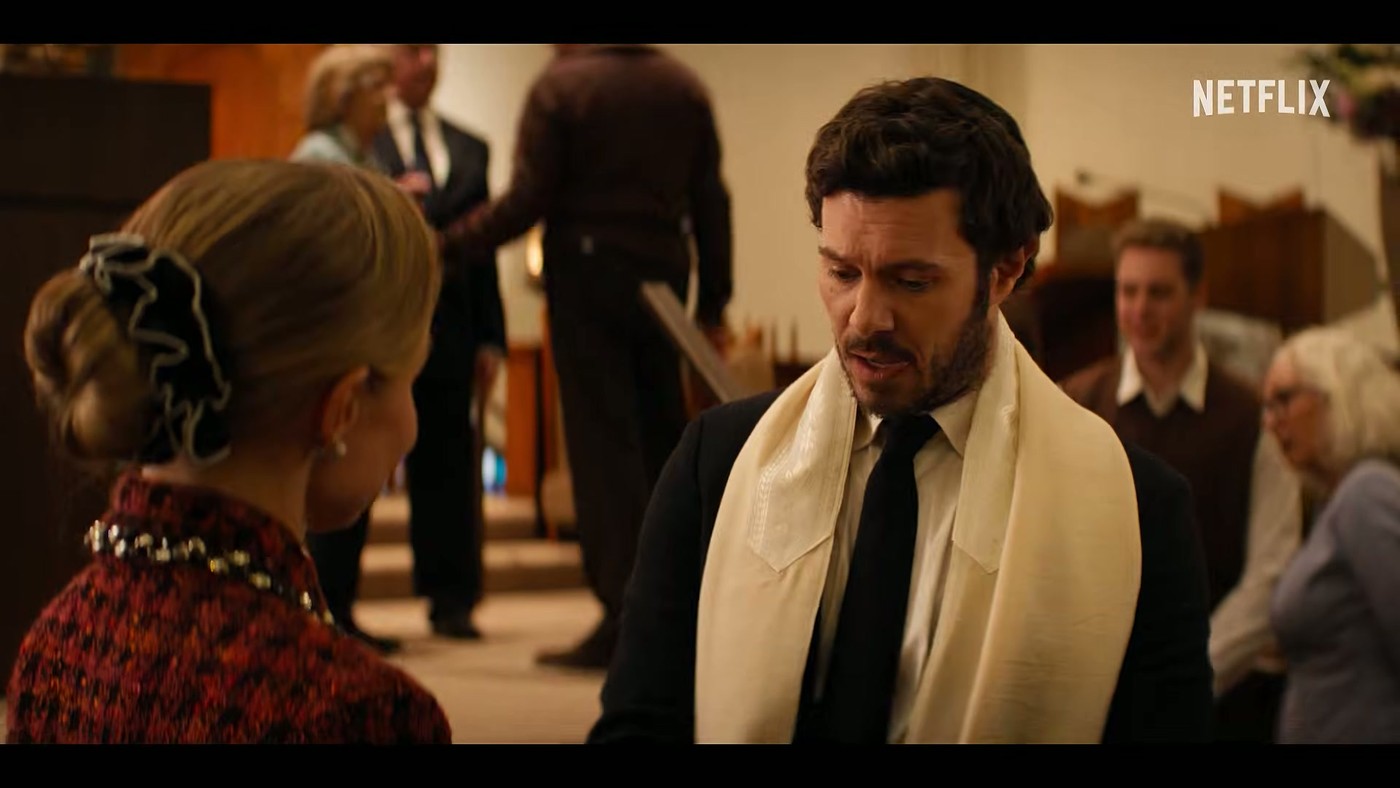 Adam Brody as Noah wearing a tallit and facing Kristen Bell as Joanne inside a synagogue