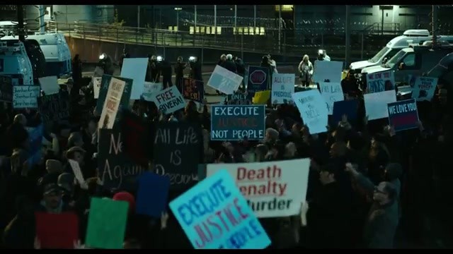 A nighttime protest crowd holding signs about the death penalty and execution