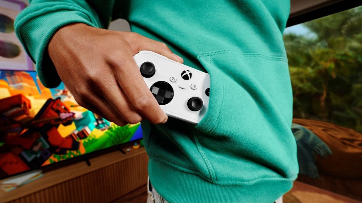 A hand pulling the white Xbox Nano Controller out of a hoodie pocket